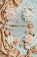 The Garment — full cover, centered gold title, blush-peach florals and satin ribbon on mint marble